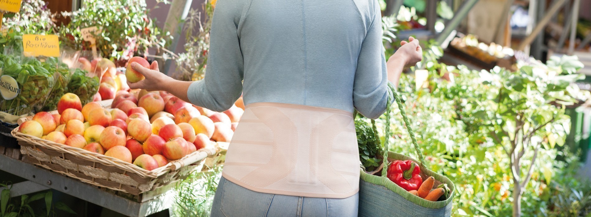 Mulher no supermercado a usar uma ortótese lombar