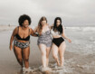 Drei Freundinnen spazieren zusammen am Strand entlang 