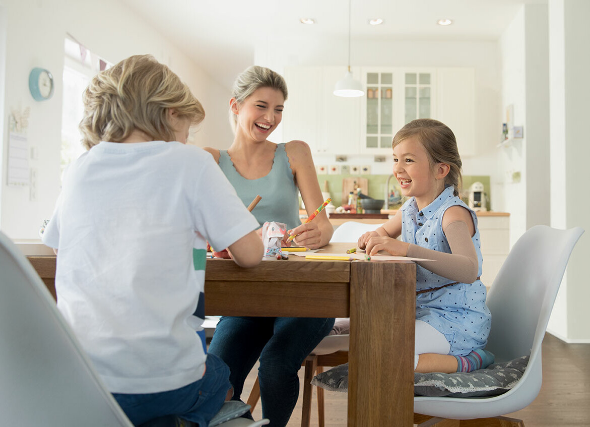 Mutter und Kind sitzen zusammen am Esstisch und haben Spaß