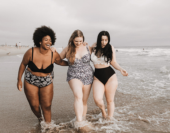 Drei Freundinnen spazieren zusammen am Strand entlang Drei Freundinnen spazieren zusammen am Strand entlang