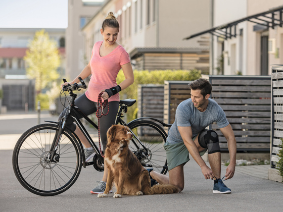 Artros  En kvinna och en man med cykel motionerar en hund
