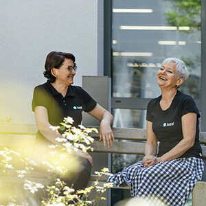Mitarbeiterinnen auf einer Bank in der Sonne