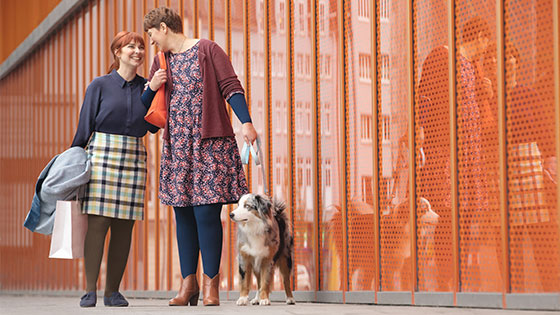 Oedema therapy Two women take their dog for a walk. They are wearing flat-knit compression garments.