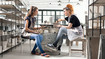 Two women are sitting at a table making pottery. They are wearing compression garments with a dip-dye look.