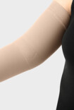 Una mujer lleva una manga de compresión de Juzo con la zona funcional del codo