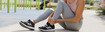 A woman sits on the floor holding her ankle