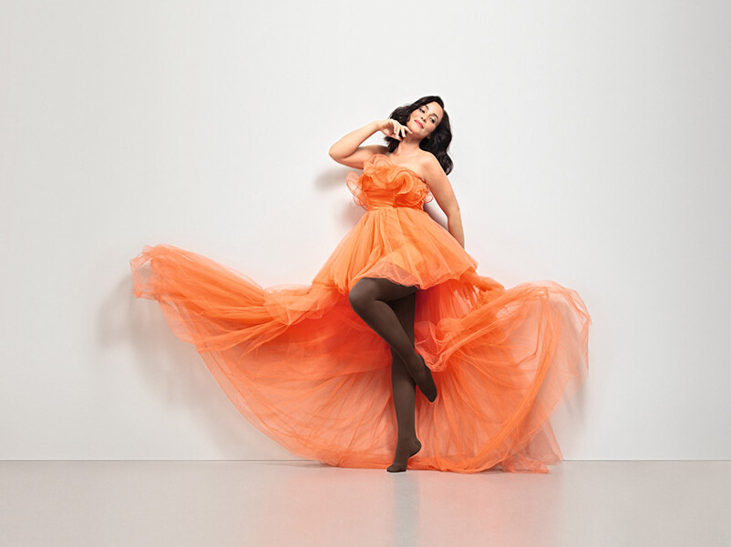 Juzo Inspiration Frau trägt ein orangenes Tüllkleid und den Juzo Inspiration in Kakao