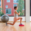 A woman doing a lunge, lowering her back leg to just above the ground