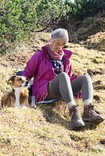 Woman and dog sitting on a hill.