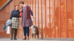 Two women take their dog for a walk. They are wearing flat-knit compression garments.