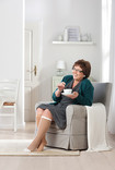 Kvinna med Juzo Ulcer Pro-strumpan sitter i en fåtölj och dricker te