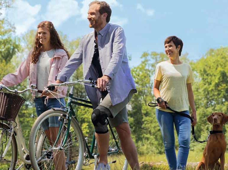 Zwei Fahrradfahrer und eine Frau mit Hund stehen nebeneinander